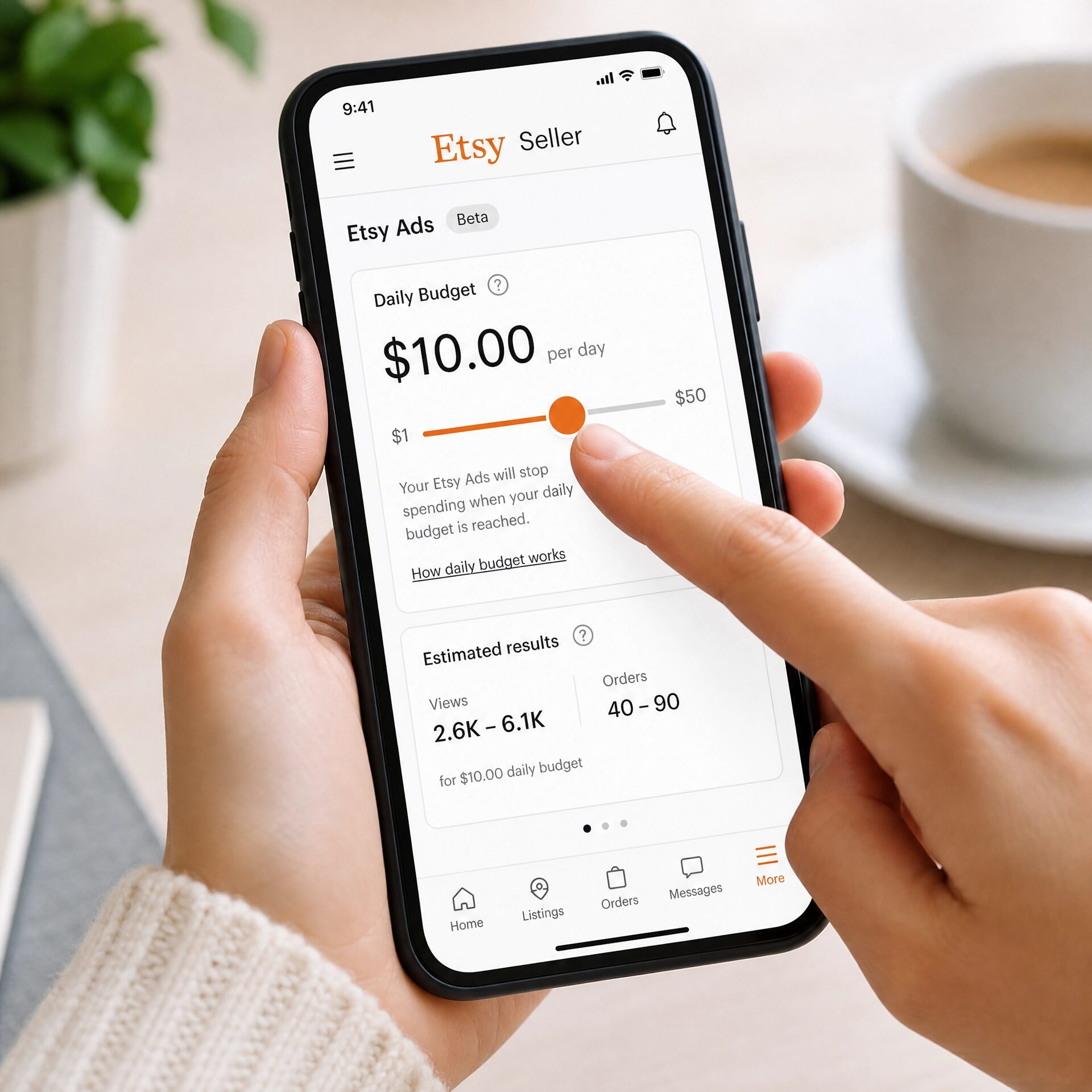 Close-up of hands adjusting the daily budget slider on the Etsy Seller app on a smartphone.Â