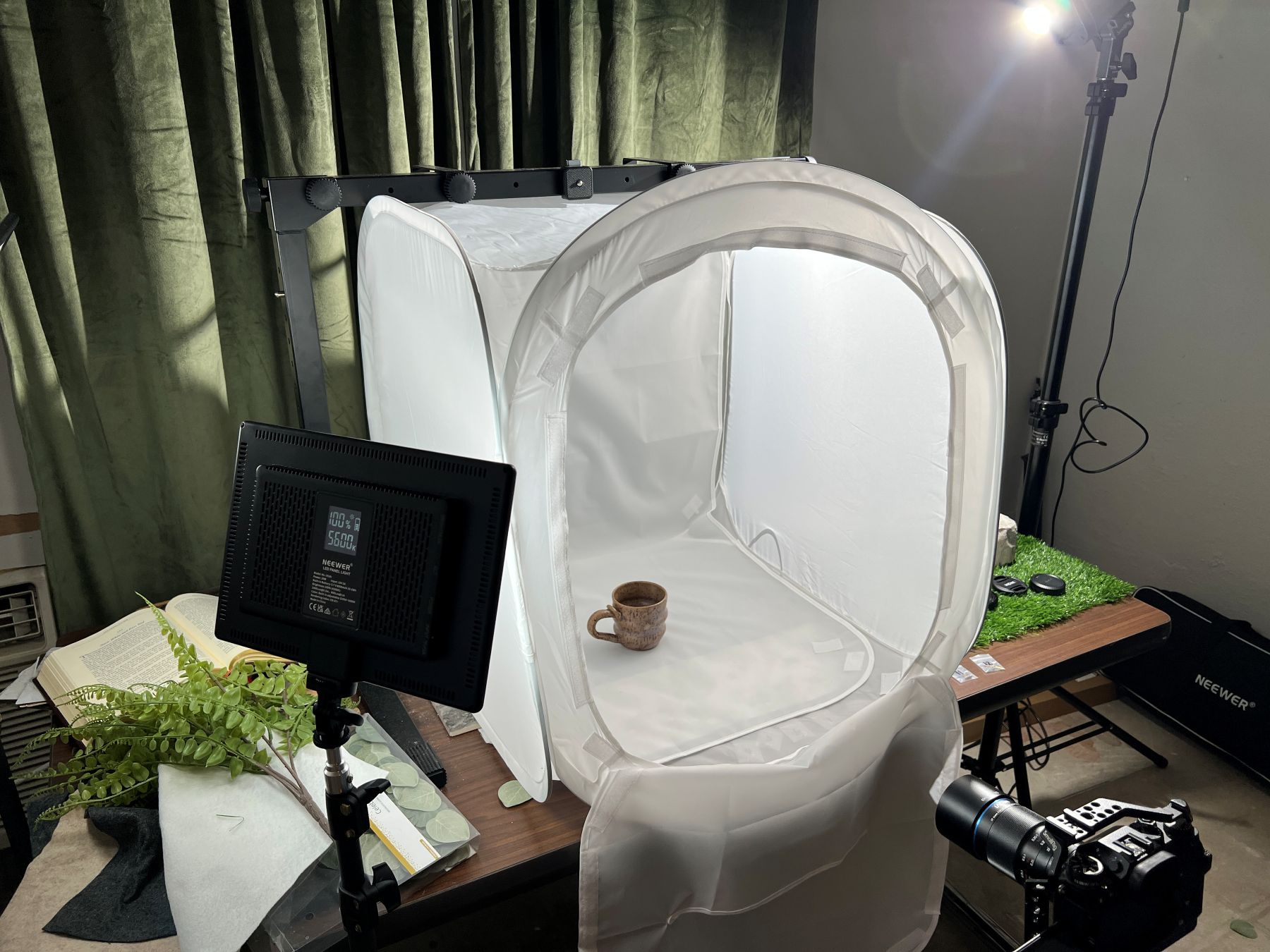 A professional product photography setup featuring a light tent, camera on a tripod, and a coffee mug being photographed.